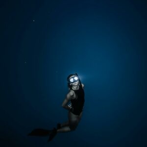 Unrecognizable woman diving in blue sea water